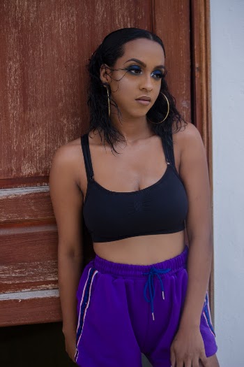 Photo of Woman in Black Sports Bra and Purple Shorts Posing by Wooden Door