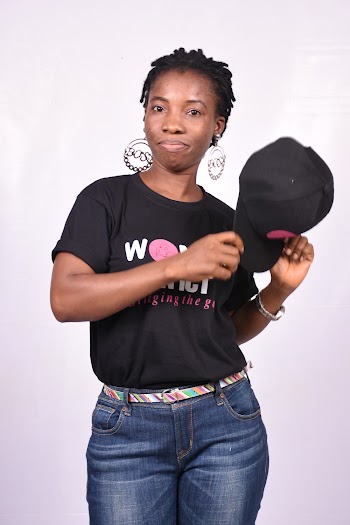 Photo of Woman in Black T-shirt and Blue Jeans Posing In Front of White Background While Holding Black Cap 