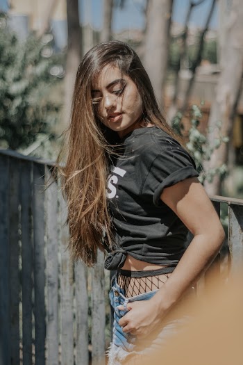 Photo of Woman in Black T-shirt Standing Beside Wooden Fence