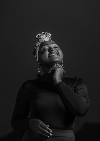 Photo of Woman in Black Top and Dangle Earrings on a Black Background