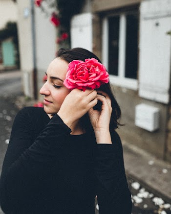 Photo of Woman in Black Top Wearing Pink Flower on Her Head