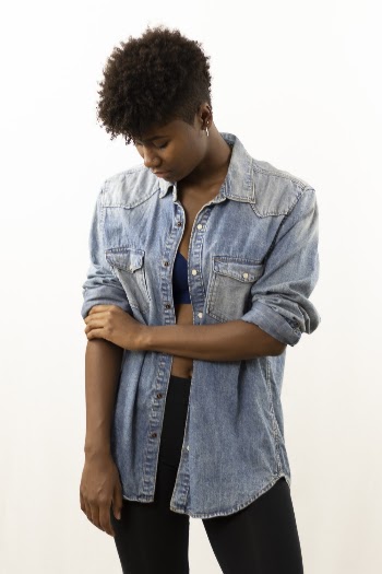 Photo of Woman in Blue Denim Button Down Shirt and Black Bottoms Pulling Up Her Sleeve