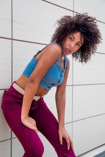 Photo of Woman in Blue Denim Crop Top and Purple Jeans Leaning at Tiled Wall