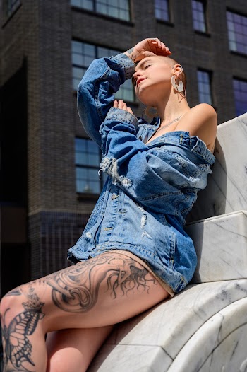 Photo of Woman in Blue Denim Jacket Leaning beside a Gray Building