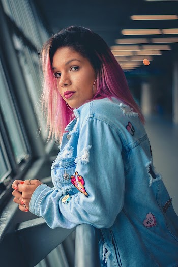 Photo of Woman in Blue Denim Jacket Leaning on Metal Railing