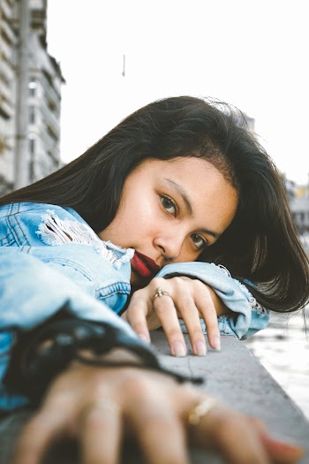 Photo of Woman in Blue Denim Jacket Leaning on Stone Railing