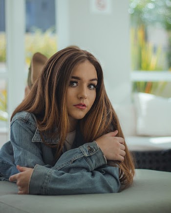 Photo of Woman In Blue Denim Jacket Lying Down on Stomach on Grey Couch