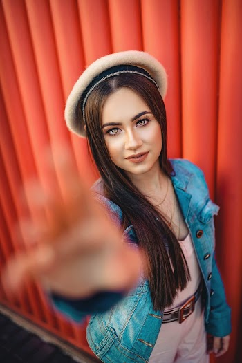 Photo of Woman in Blue Denim Jacket Posing While Reaching Out Her Hand
