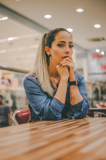 Photo of Woman in Blue Denim Top Sitting by Table 