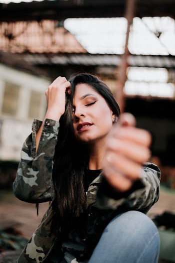Photo of Woman in Camouflage Jacket Posing with Her Eyes Closed