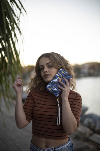 Photo of Woman in Crop Top Holding Clutch Purse by Her Face