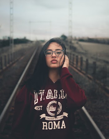 Photo of Woman in Eyeglasses Standing in the Middle of a Train Track