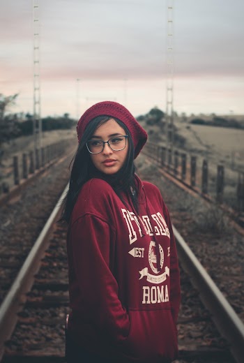 Photo of Woman in Eyeglasses Standing in the Middle of a Train Track