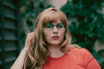 Photo of Woman in Eyeglasses Touching Her Hair With Her Left Hand