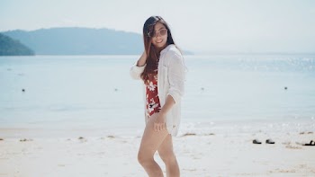 Photo of Woman in Floral Swimsuit and White Dress Shirt Posing at the Beach