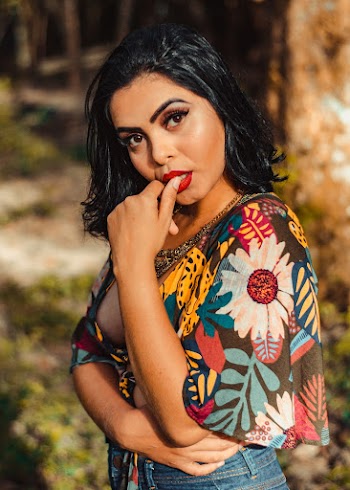 Photo of Woman in Floral Top Posing While Biting Her Thumb