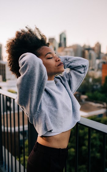 Photo of Woman in Gray Sweatshirt and Black Pants Posing With Her Eyes Closed