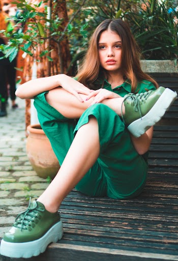 Photo of Woman in Green Outfit Sitting on Wooden Surface