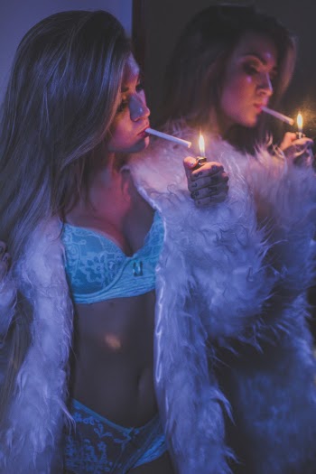 Photo of Woman in Lingerie Lighting Cigarette Beside Wall Mirror
