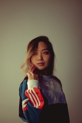 Photo of Woman in Multicolored Sweatshirt Posing In Front of White Background While Looking Away