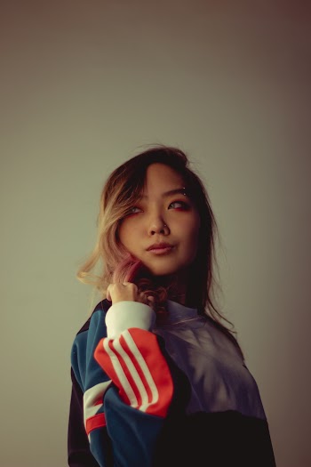 Photo of Woman in Multicolored Sweatshirt Posing In Front of White Background While Looking Away