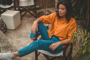 Photo of Woman in Mustard Collared Shirt Sitting on Wooden Armchair