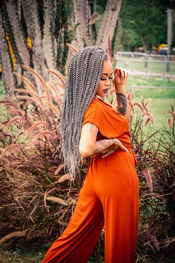 Photo of Woman in Orange Jumpsuit Posing Next to Long Grass