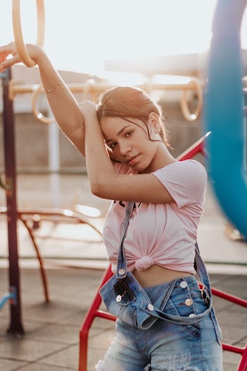 Photo of Woman in Pink T-shirt and Blue Dungaree Posing by Jungle Gym