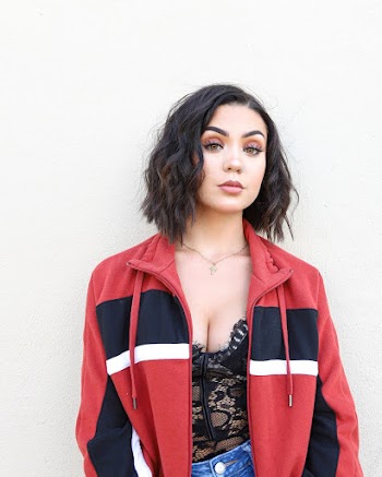 Photo of Woman in Red and Black Zip-up Jacket Posing In Front of White Background