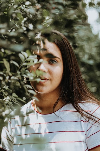 Photo of Woman in Red and White Striped T-shirt Posing Behind Green Leaves