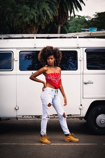 Photo of Woman in Red Bandanna Top and Blue Distressed Denim Jeans Standing in Front of Parked VW Van