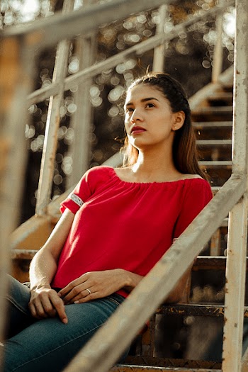 Photo of Woman in Red Blouse Sitting on Metal Staircase