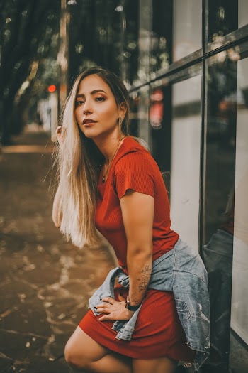 Photo of Woman in Red Dress Leaning on Glass Wall Posing