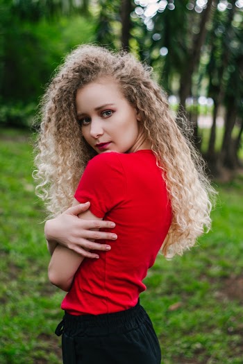 Photo of Woman in Red T-shirt and Black Bottoms Posing