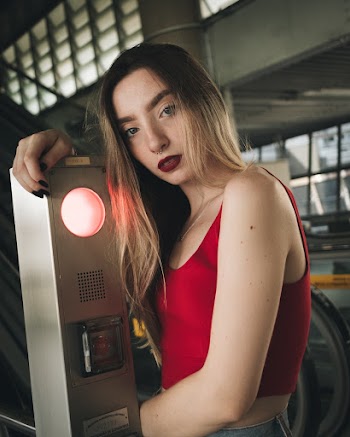 Photo of Woman in Red Tank Top Standing by an Escalator Stop Button Machine