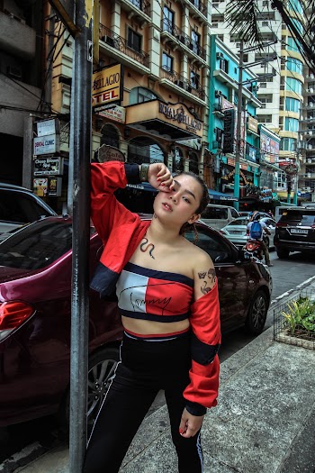 Photo of Woman in Tommy Hilfiger Outfit Leaning on Metal Sign Post on Side Walk by the Street