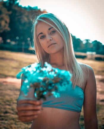 Photo of Woman in Tube Top Holding Out Blue Flowers
