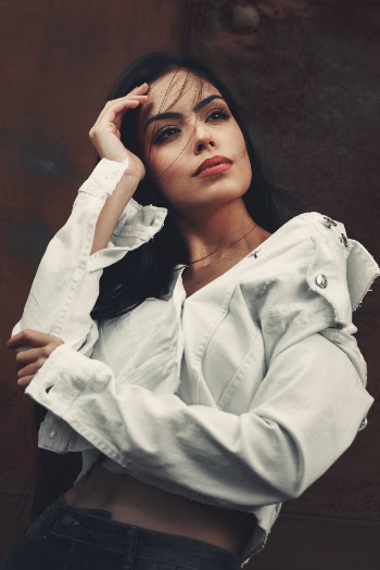 Photo of Woman in White Denim Jacket and Black Jeans Posing