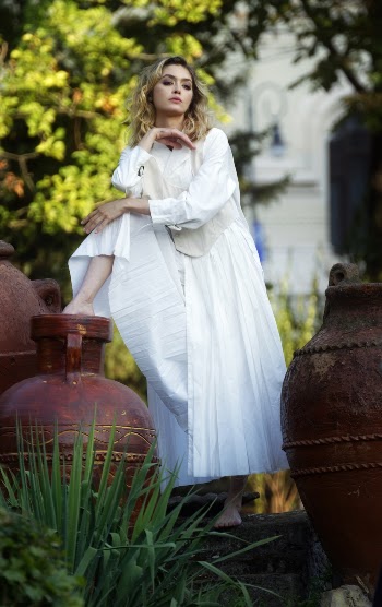 Photo of Woman in White Dress Posing By Clay Jars