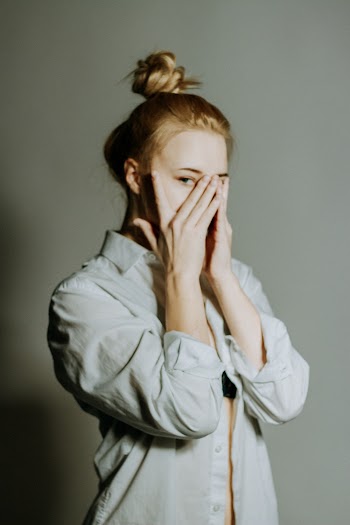 Photo of Woman in White Dress Shirt Hiding Her Face With Her Hands