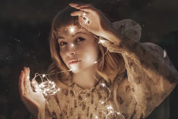 Photo of Woman in White Floral Dress Holding Turned-on String Lights