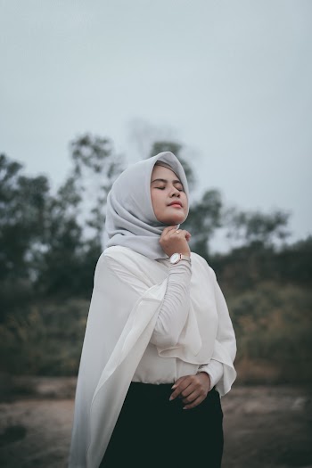 Photo of Woman in White Long-sleeved Shirt and Grey Hijab Posing With Her Eyes Closed
