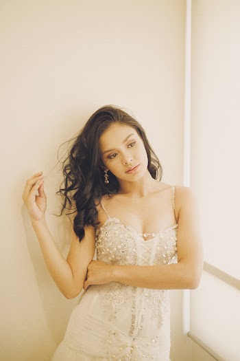 Photo of Woman in White Spaghetti Strap Dress Standing by White Wall