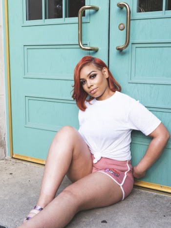 Photo of Woman in White T-shirt and Pink Shorts Sitting on Floor While Leaning on Door