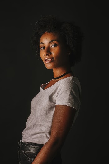 Photo of Woman in White T-Shirt Standing in Front of Black Background