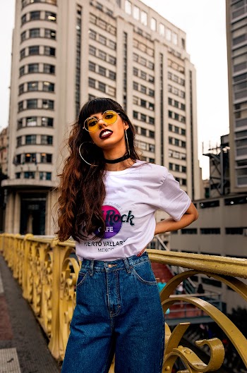 Photo of Woman in White Top and Blue Jeans Posing with High-rise Building in the Background