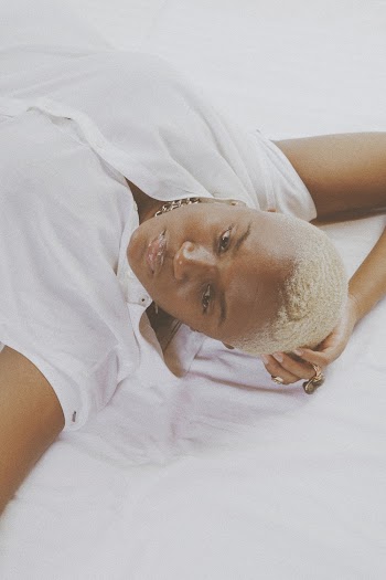 Photo of Woman in White Top Lying on Bedspread