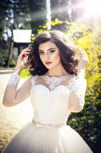 Photo of Woman in White Wedding Dress Holding Her Hair