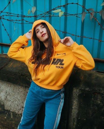 Photo of Woman in Yellow Hoodie and Blue Pants Posing