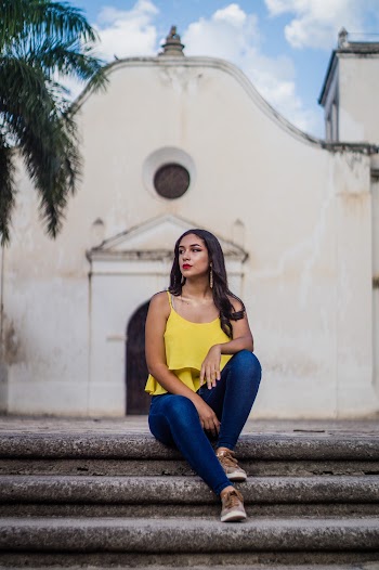 Photo of Woman in Yellow Sleeveless Top and Blue Jeans Sits on Staircase with White Building in the Background